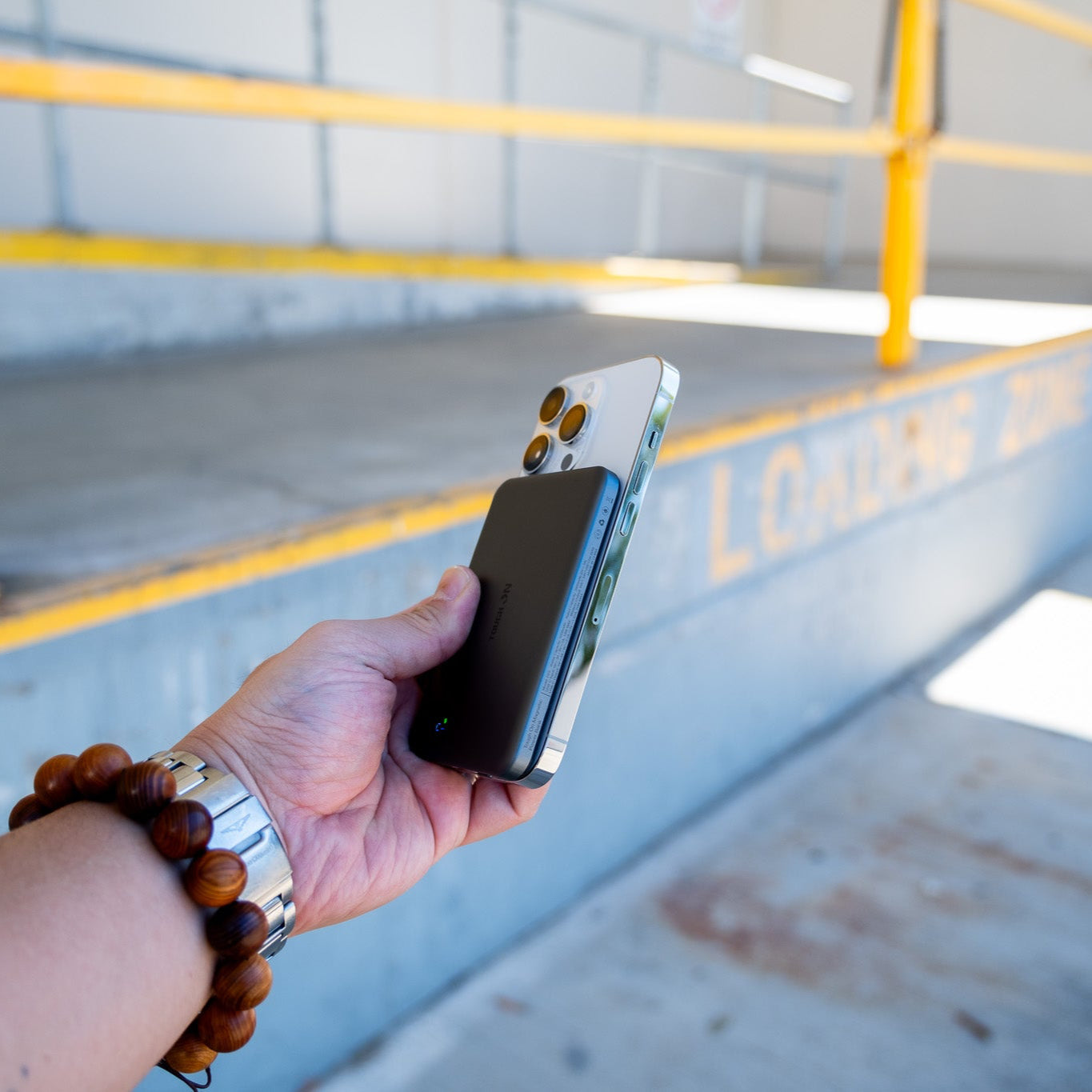 Hand holding a smartphone with a reflective surface in an industrial setting
