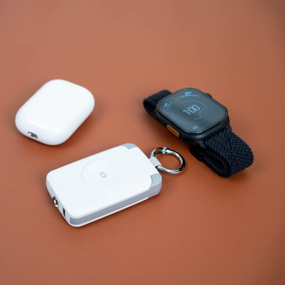 White PTC WatchGo 2000 with an Apple Watch and AirPods on a terracotta background