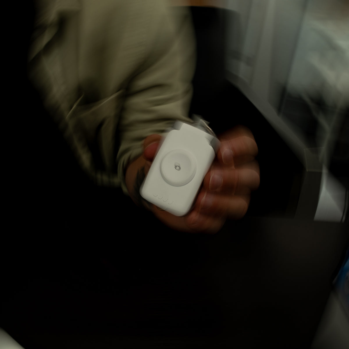 White PTC WatchGo 2000 power bank held in one hand against a dark background