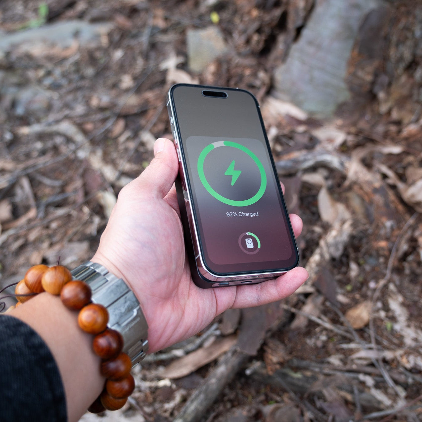 Hand holding a smartphone with a charging app on a natural background