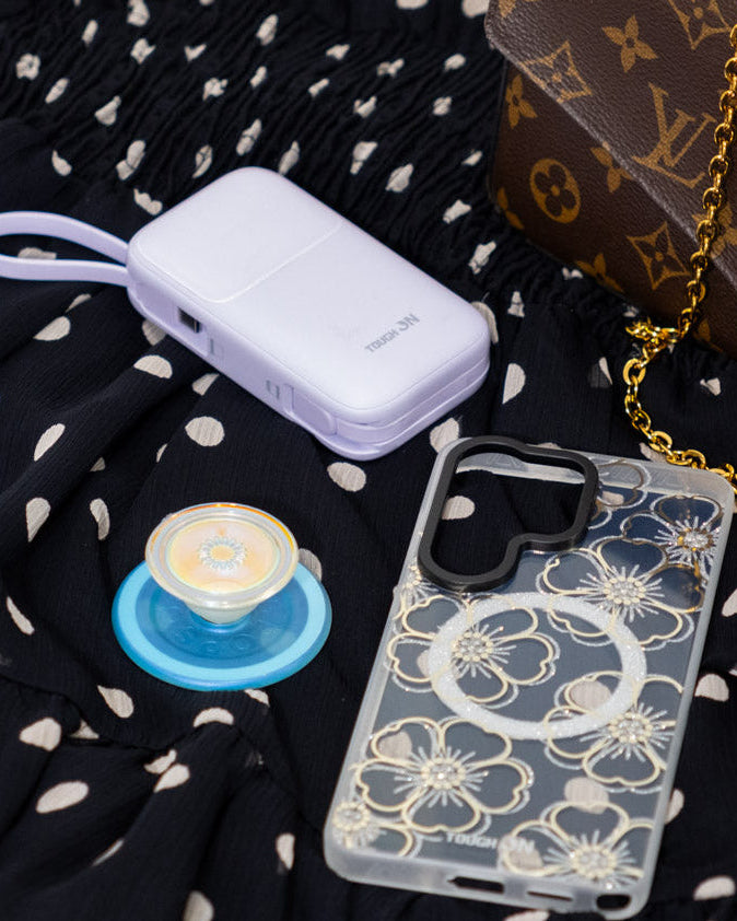 Phone case, small container, and blue object on a black polka dot fabric with a brown patterned bag.