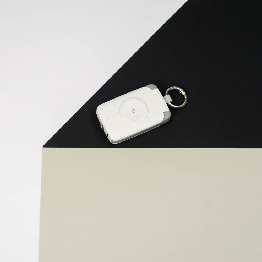 White PTC WatchGo 2000 power bank with keyring on a black and cream backdrop