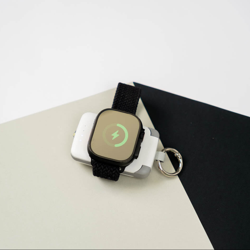 Apple Watch Ultra charging magnetically on a white PTC WatchGo 2000 power bank