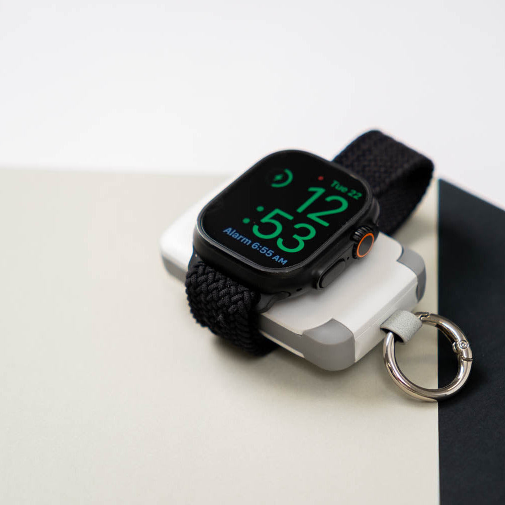 Apple Watch showing the time while it charges on a white PTC WatchGo 2000