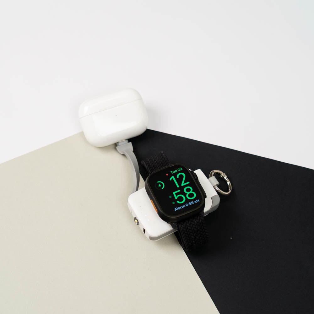 Apple Watch charging on a white PTC WatchGo 2000 next to AirPods