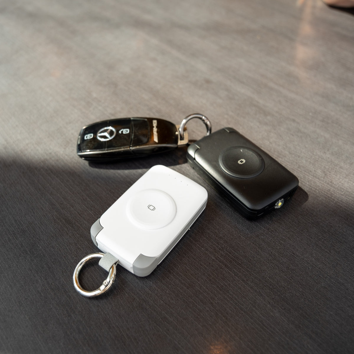 White PTC WatchGo 2000 power bank on a desk beside a black car key