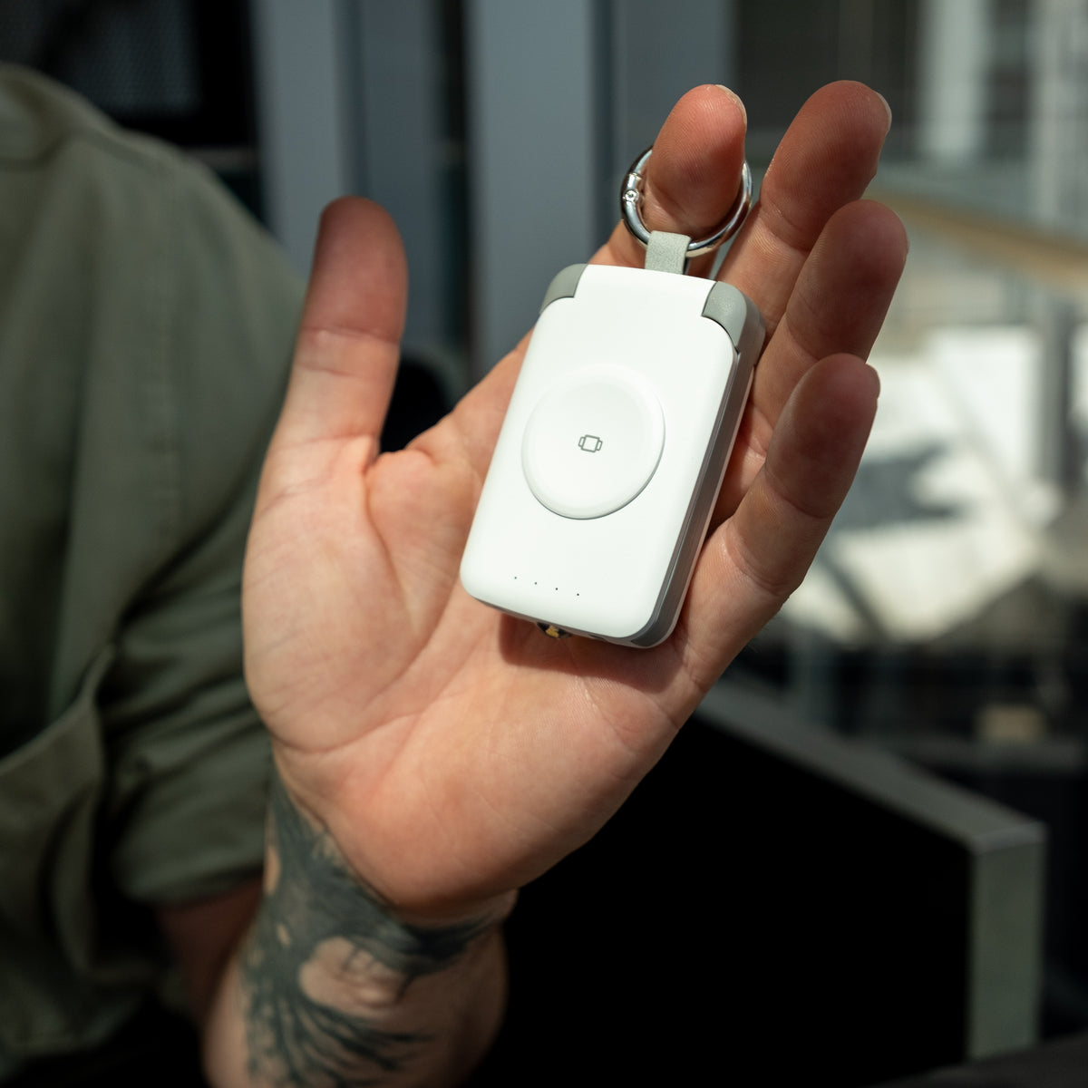 Man holding a white PTC WatchGo 2000 power bank in his hand on the street