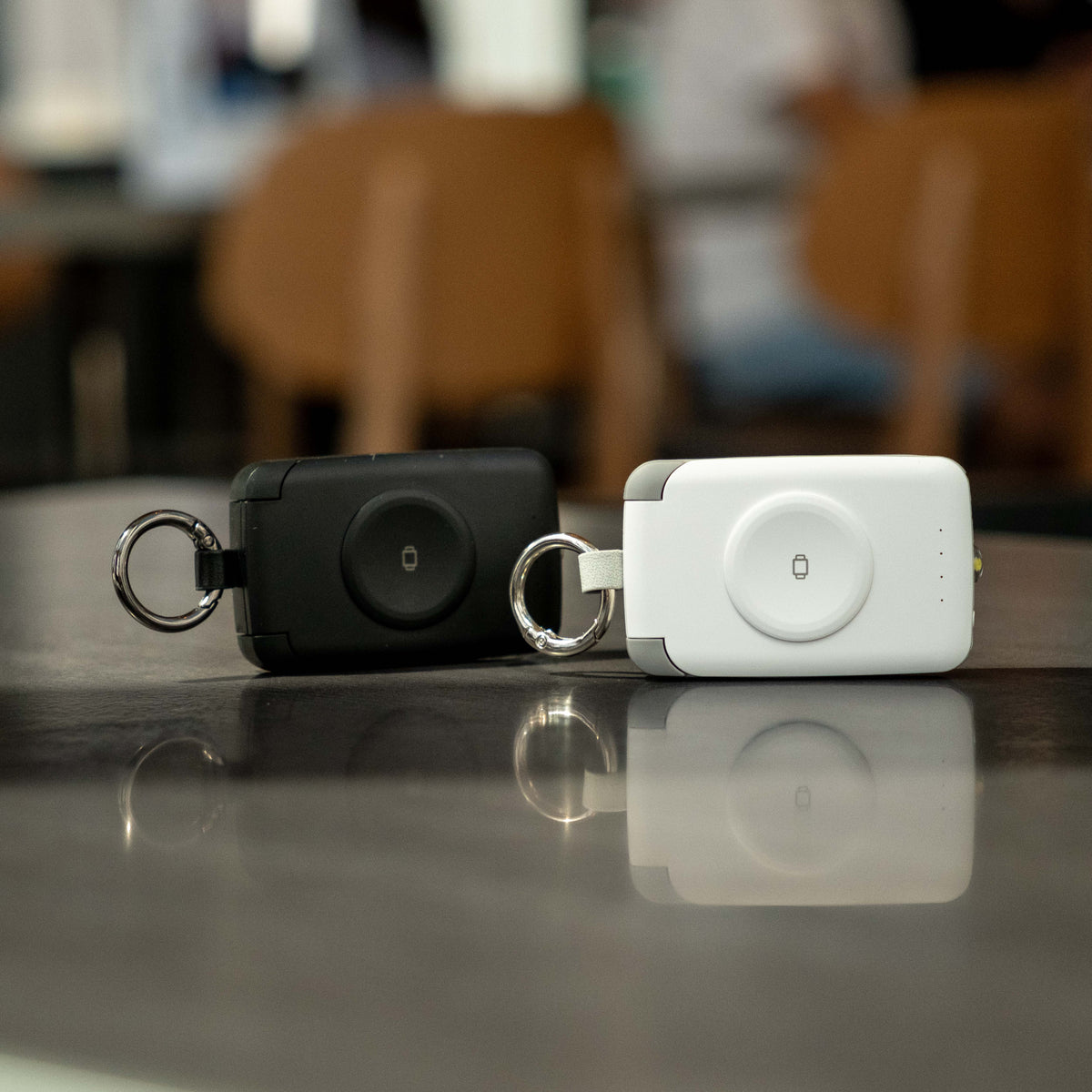 Black and white PTC WatchGo 2000 power banks standing side by side on a polished table