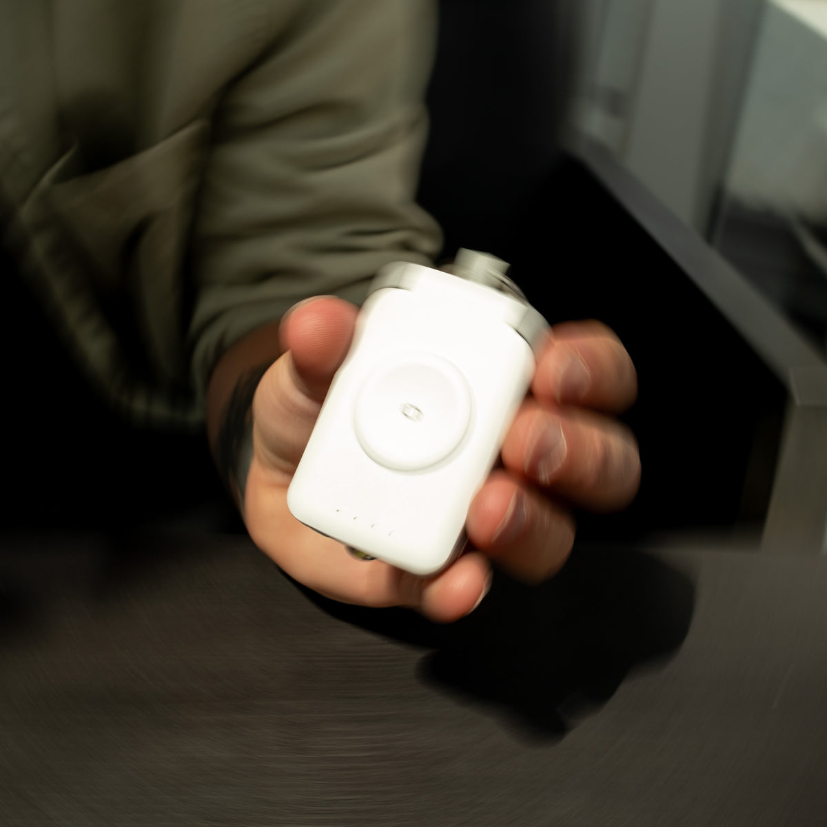 White PTC WatchGo 2000 power bank held in one hand, showing the magnetic charging pad