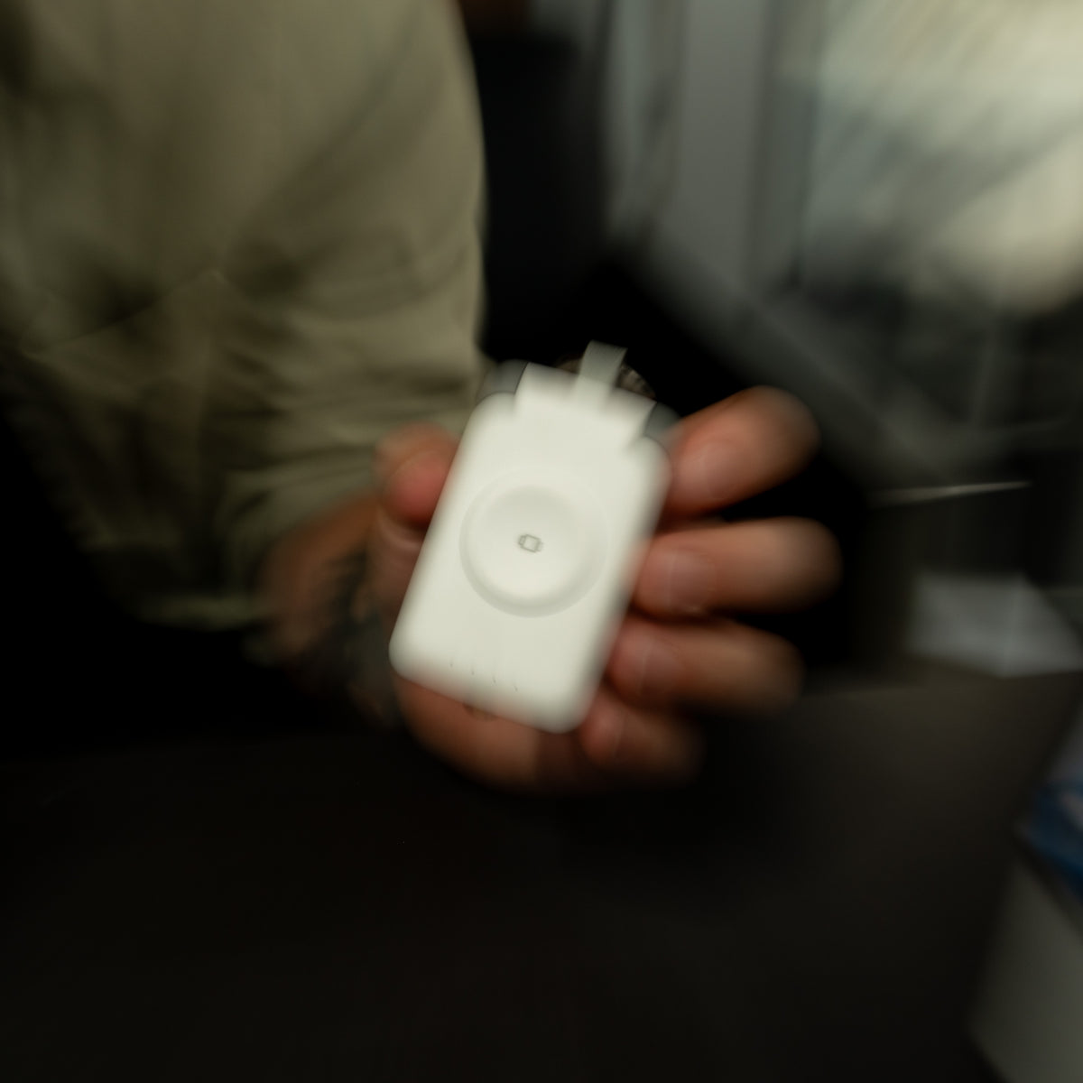 White PTC WatchGo 2000 power bank held in a hand to show how small it is