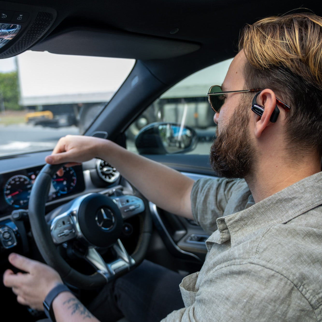 Person wearing a black wireless earbud with sunglasses on.