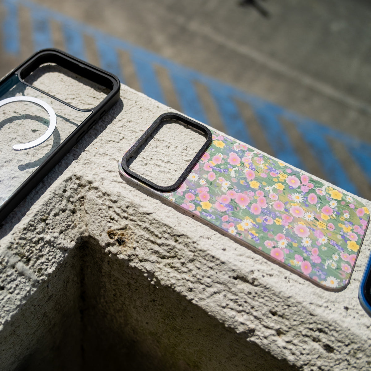 Close up of a custom skin MagSafe iPhone case on concrete beside a wildflower skin design